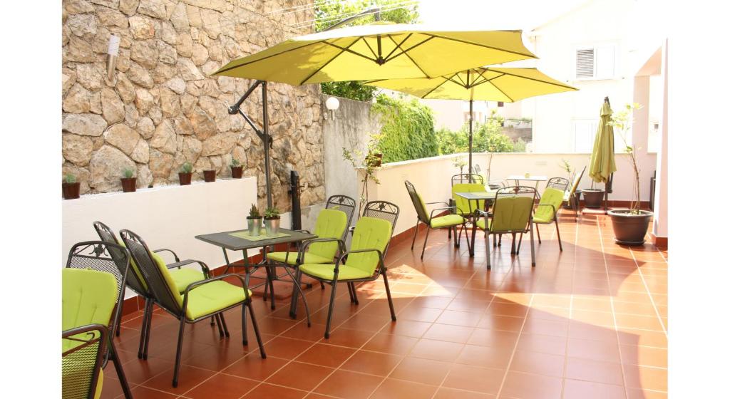um pátio com mesas, cadeiras e guarda-sóis amarelos em Guest House Sol em Cavtat
