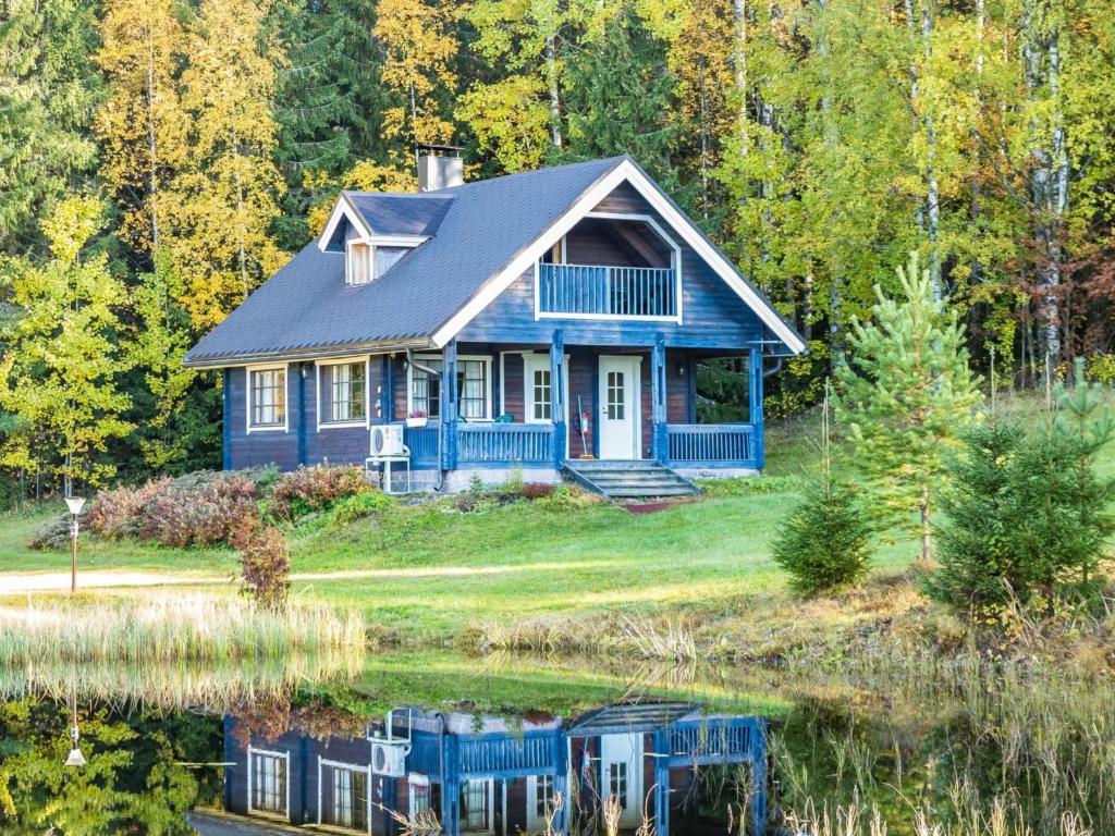 a blue house with a pond in front of it at Holiday Home Iltarusko by Interhome in Ruokonen