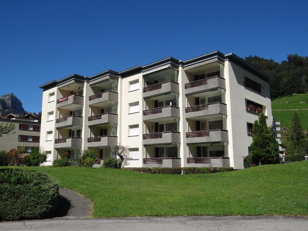 um grande edifício de apartamentos branco com um relvado verde em Apartment Sunnmatt Süd 412 by Interhome em Engelberg