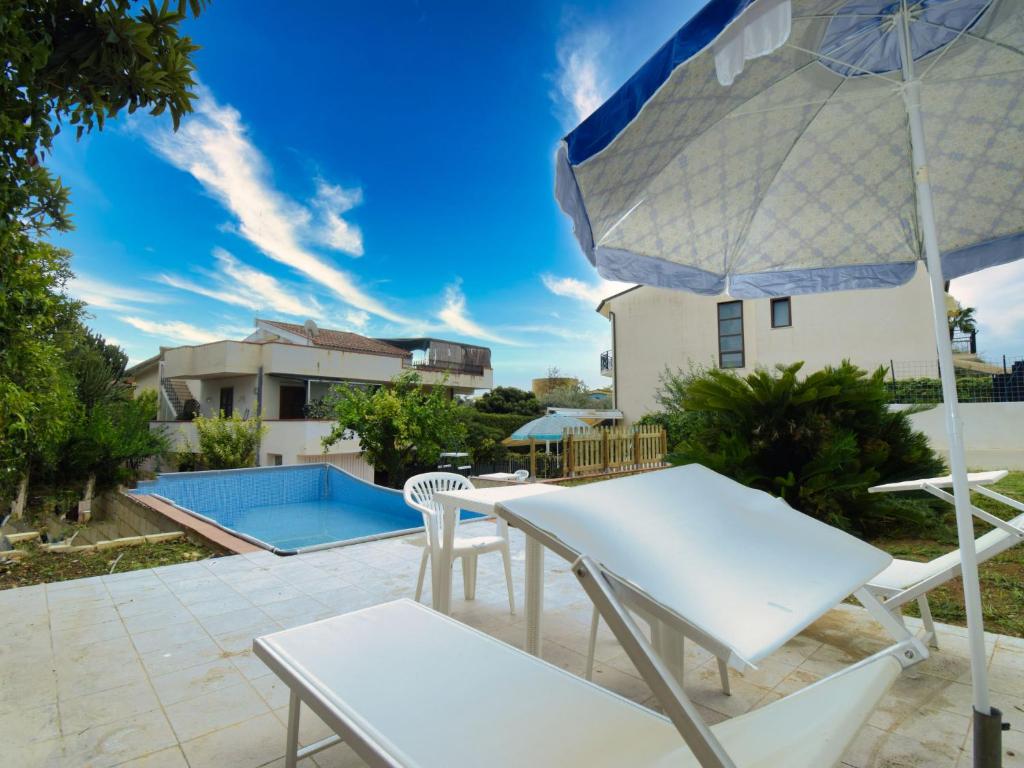 eine Terrasse mit einem Tisch, Stühlen und einem Sonnenschirm in der Unterkunft Holiday Home La Grande Musa by Interhome in Fontane Bianche