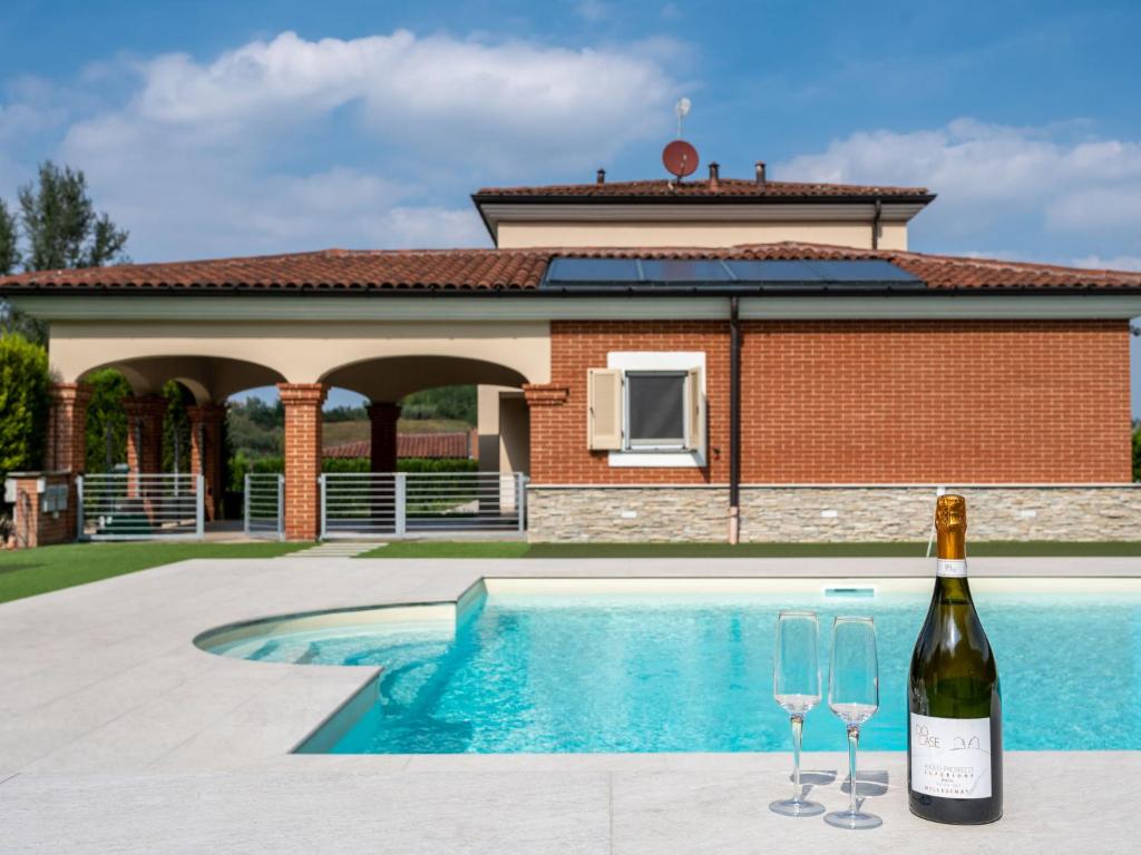 uma garrafa de vinho e dois copos ao lado de uma piscina em Holiday Home Appendino by Interhome em Serravalle dʼAsti