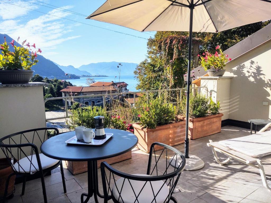 eine Terrasse mit einem Tisch, Stühlen und einem Sonnenschirm in der Unterkunft Apartment Trilocale by Interhome in Olgiasca