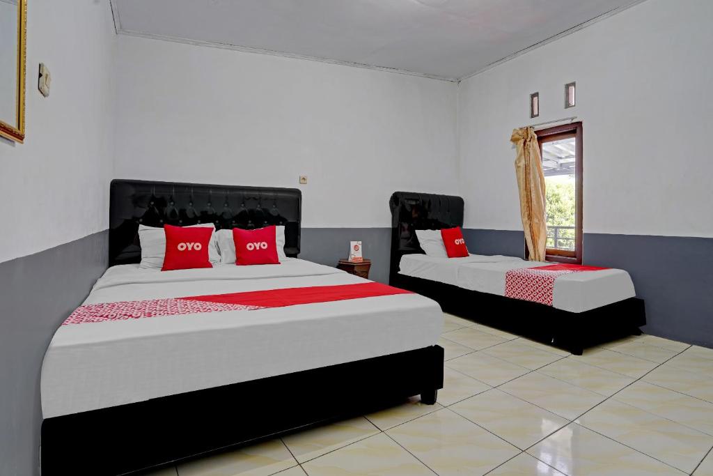 a bedroom with two beds with red pillows at SUPER OYO 90405 Penginapan Sasti Kuningan in Cirebon