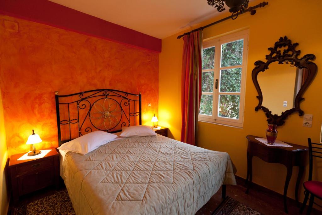 1 dormitorio con 1 cama con paredes de color naranja y ventana en Pension Eleni, en Nauplia