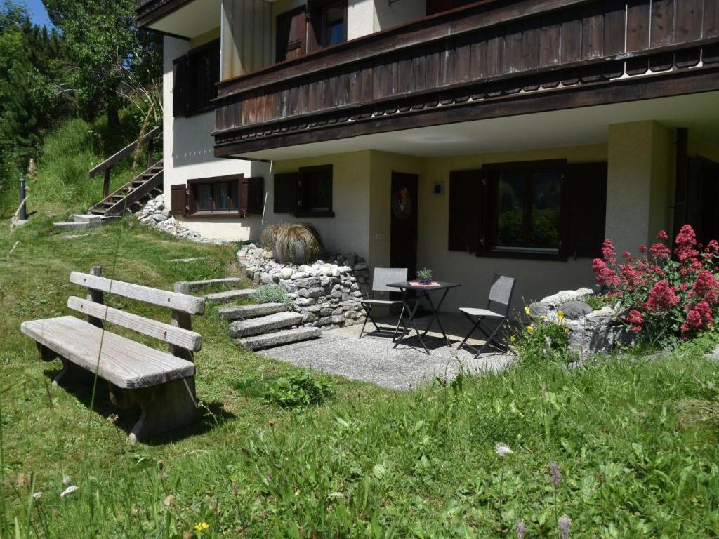 a house with a bench and a table and chairs at Apartment Am Sonnenhang by Interhome in Churwalden