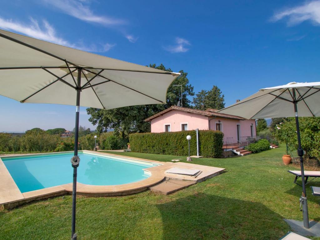 a swimming pool with two umbrellas in a yard at Villa La Quercia by Interhome in Vasanello