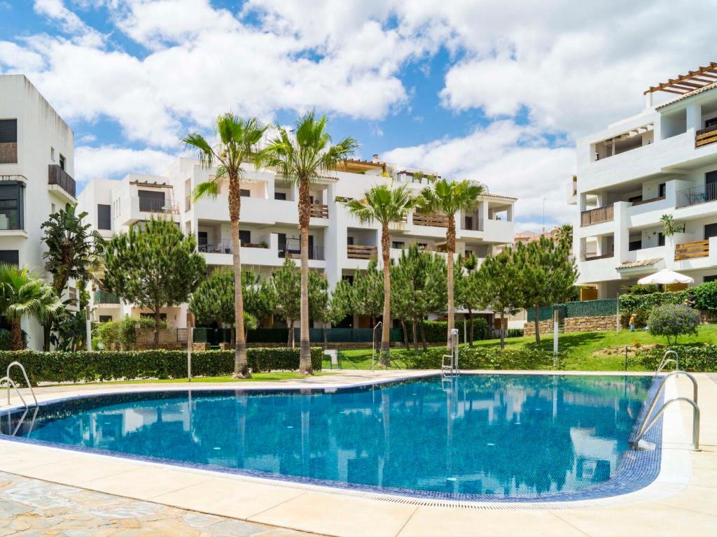 a swimming pool in front of a building with palm trees at Apartment Alamar by Interhome in Mijas Costa