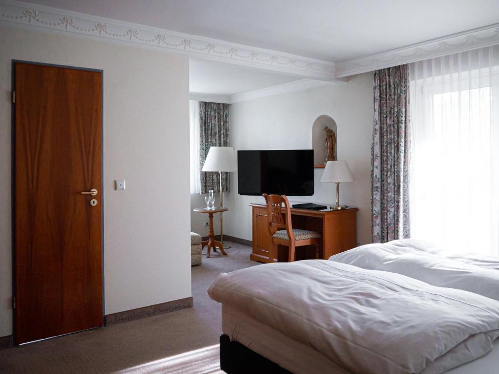 a bedroom with a bed and a flat screen tv at Parkhotel in Bad Wünnenberg