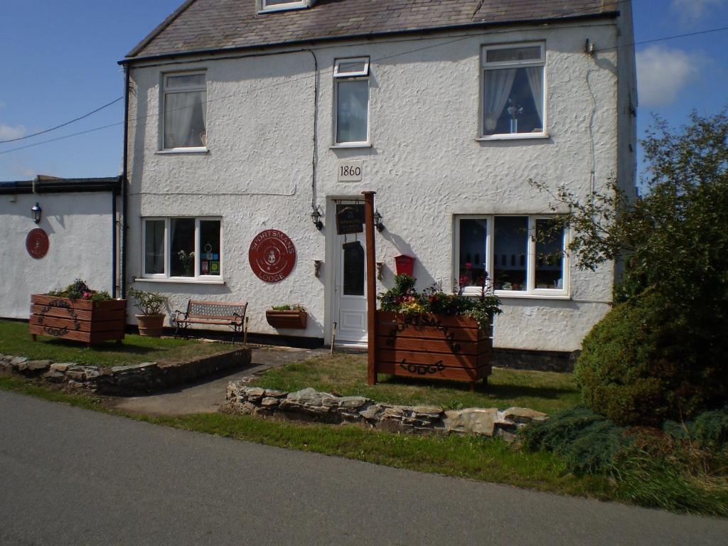 a white house with a bench in front of it at Sportsmans Lodge Bed and Breakfast in Amlwch