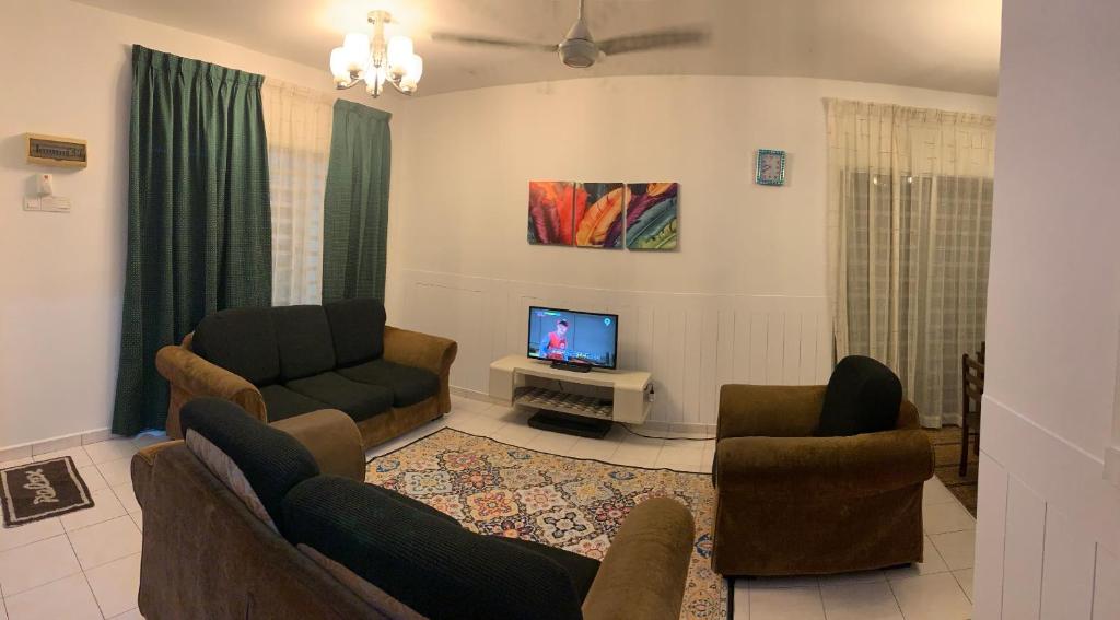 a living room with two couches and a flat screen tv at Kak's House Malay in Ipoh