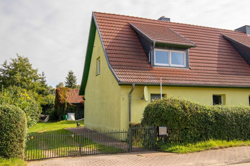 uma casa amarela com um telhado vermelho em Ferienwohnung Kogeler See em Kogel