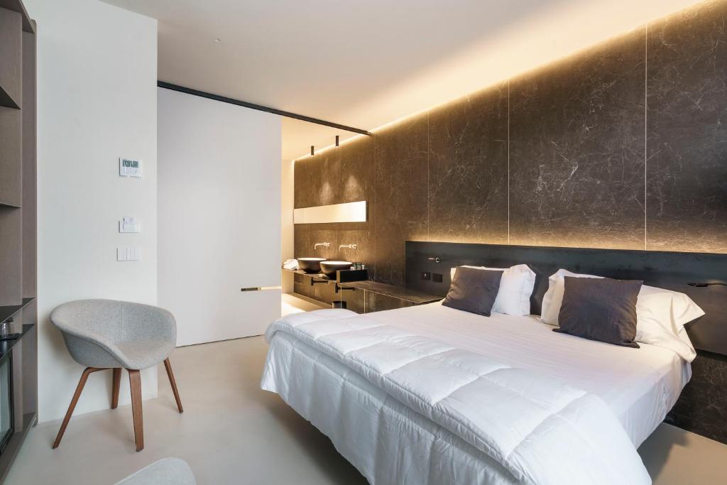 a bedroom with a large white bed and a chair at Meo Design Suites & Spa in Catania