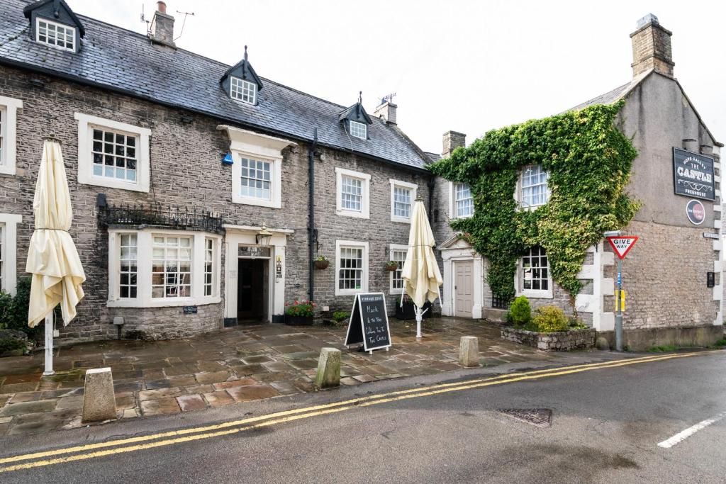 un edificio de ladrillo con sombrillas delante en The Castle by Innkeeper's Collection en Castleton