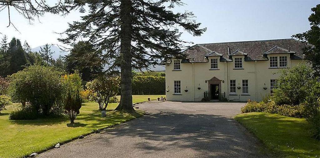 uma grande casa branca com uma árvore e uma entrada em Isle of Skye Guest House em Kyleakin