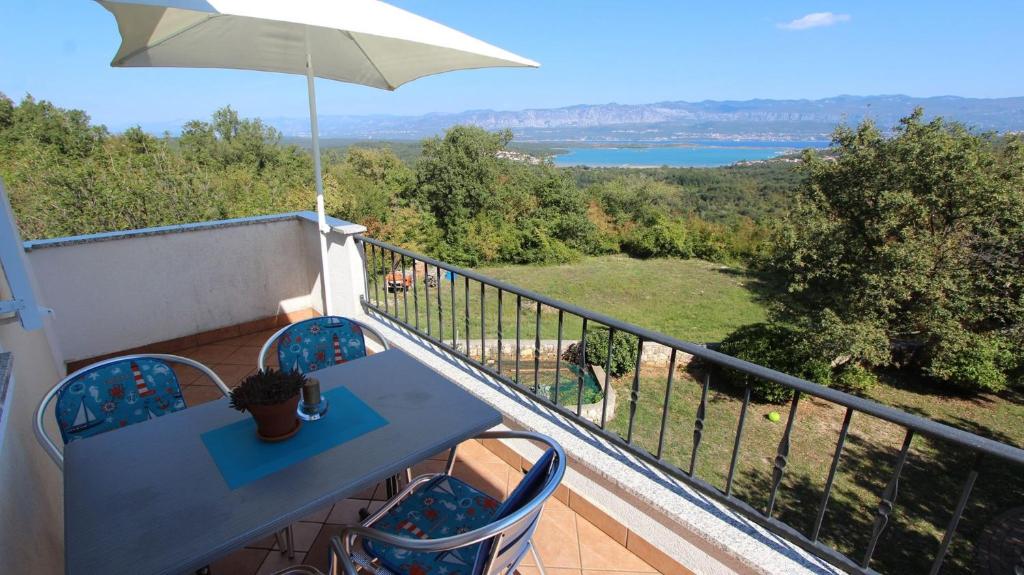 een balkon met een tafel en stoelen en uitzicht op een meer bij Apartments Damir in Sveti Ivan Dobrinjski