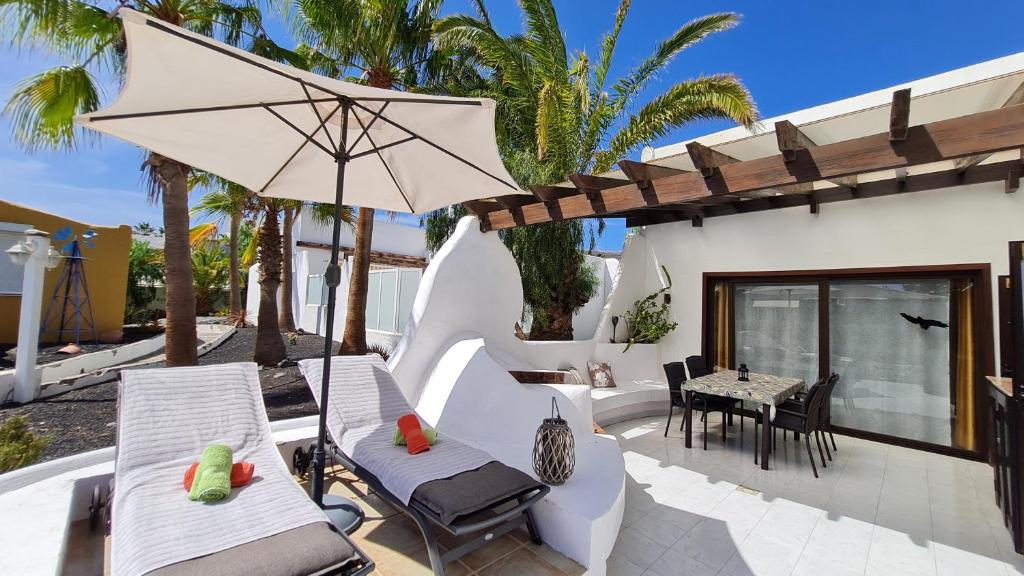 un patio con sillas, una sombrilla y una mesa en Casa EL JARDIN en Morro del Jable