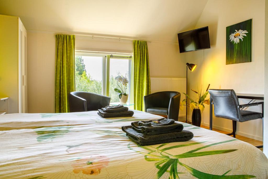 een kamer met een bed met stoelen en een raam bij Het Groene Wout in Goudriaan