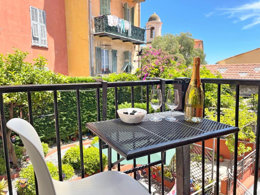a table with a bottle of wine and glasses on a balcony at Maison Bianchi - Villefranche in Villefranche-sur-Mer