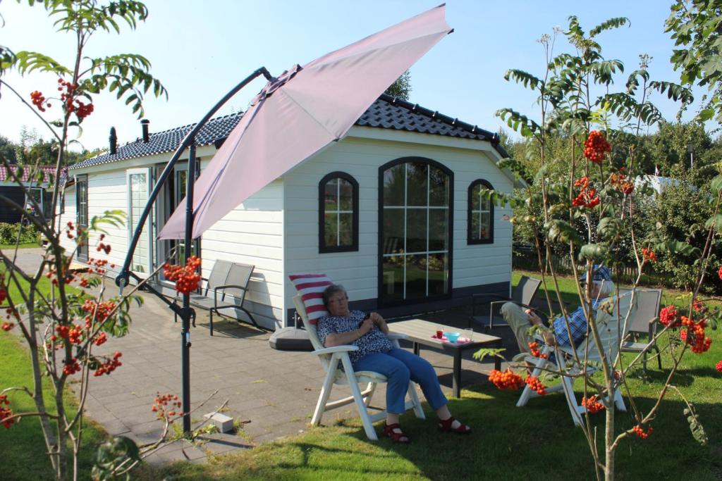 a woman sitting in a chair in front of a house at Boerderij Chalet in Drijber