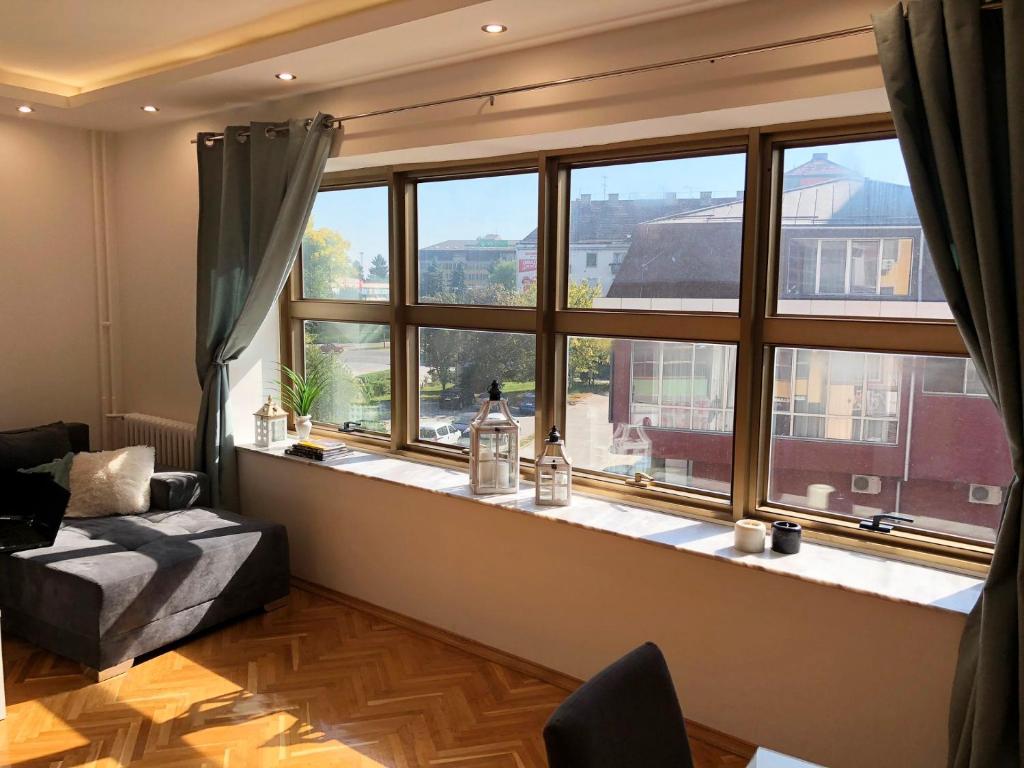 Una sala de estar con una gran ventana y un sofá. en Korzo Apartment, Subotica, en Subotica