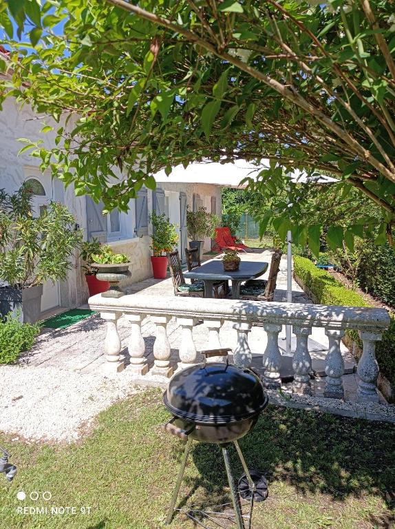 a stone bench in a yard with a table at LE CLOS DES COMPROMIS in Torsac