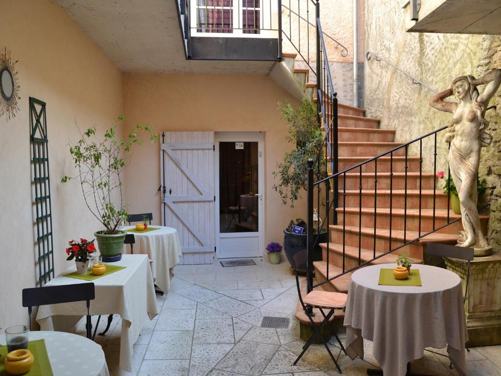 a patio with two tables and a staircase with a statue at Hostellerie De La Poste in Clamecy