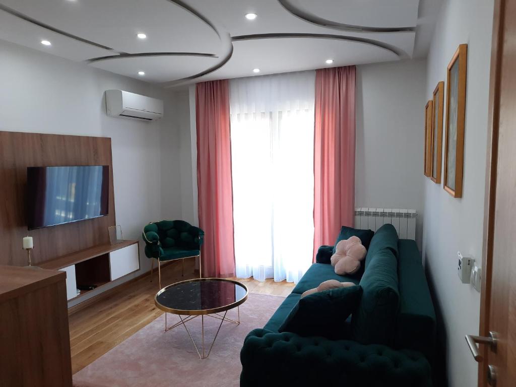 ein Wohnzimmer mit einem grünen Sofa und einem TV in der Unterkunft Apartman Orl Lux in Lukavica