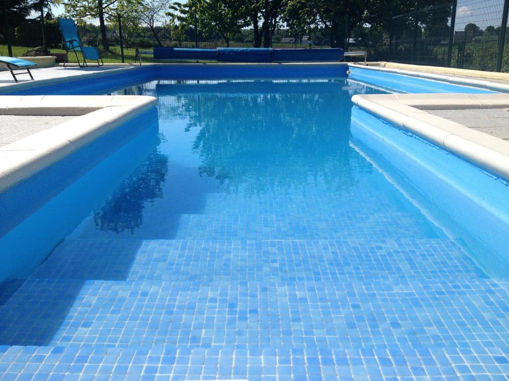 a blue swimming pool with blue tiles on it at Les Maricotais Gîte La Crécerelle in Trévérien