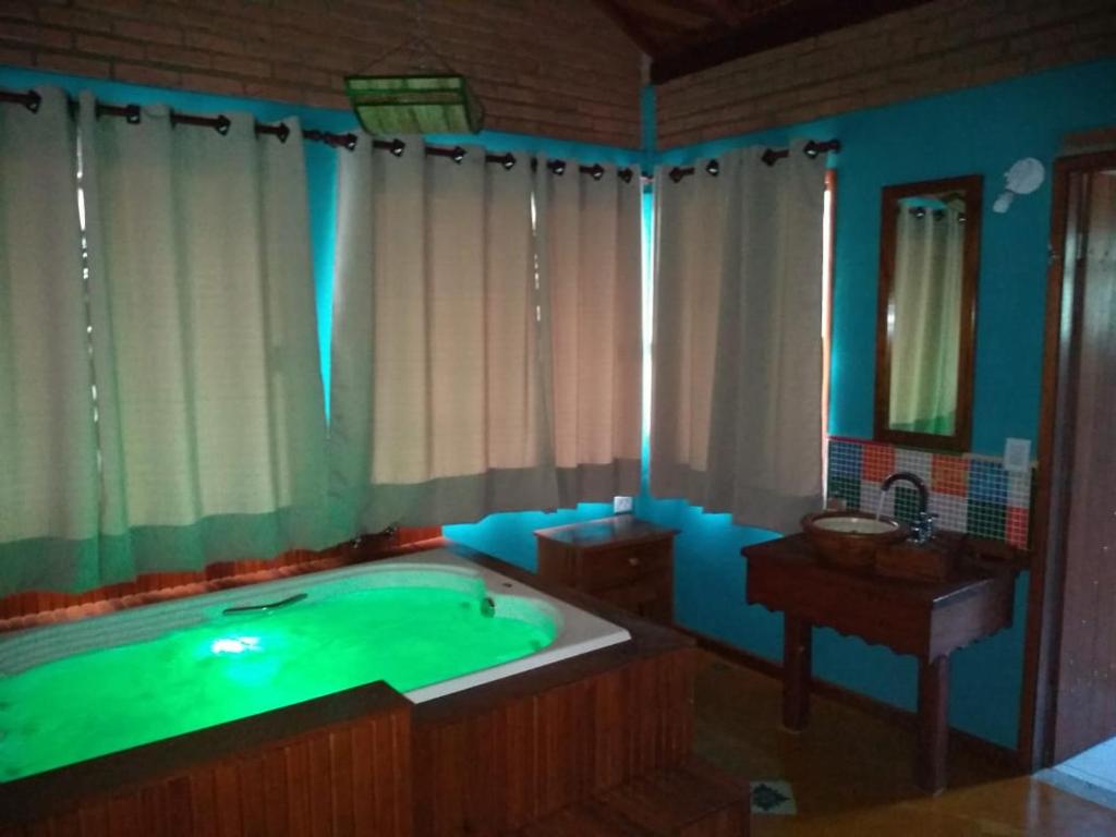 a large bathroom with a large tub with green lighting at Chalé da Sorte in Gonçalves