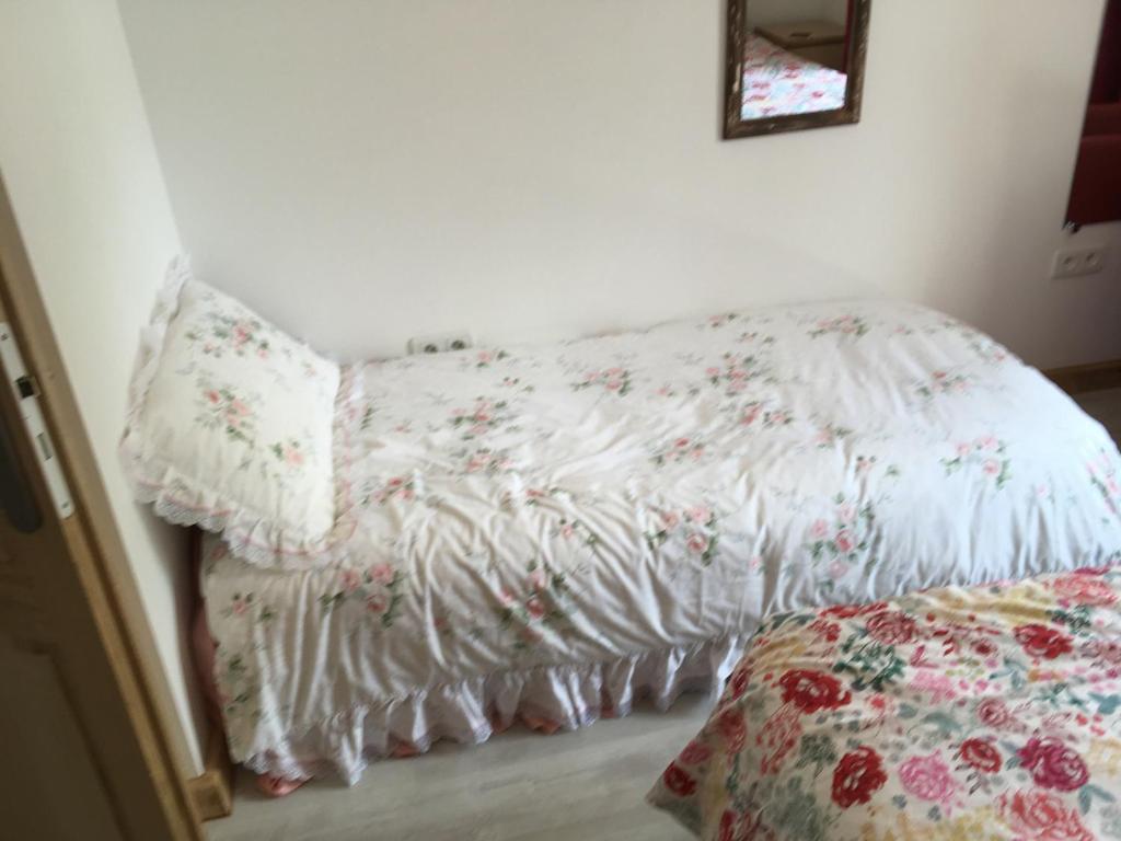 a bed with a white blanket with flowers on it at Les Maricotais Gîte La Crécerelle in Trévérien