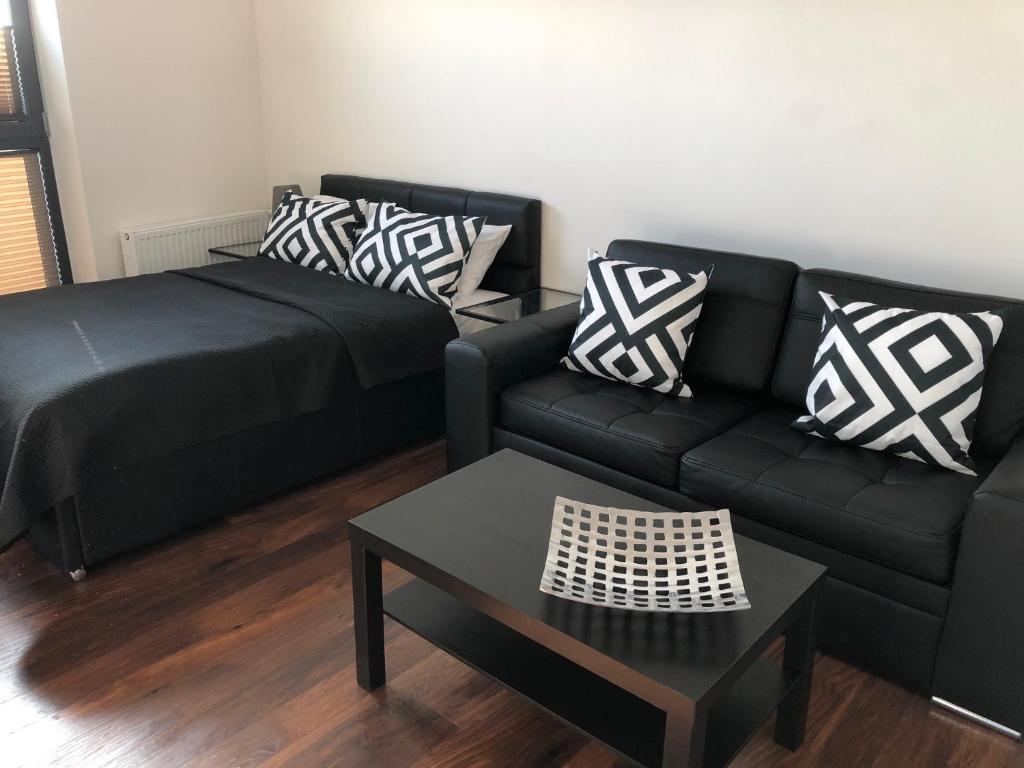 Apartamenty Platinex في كراكوف: غرفة معيشة مع أريكة سوداء وطاولة