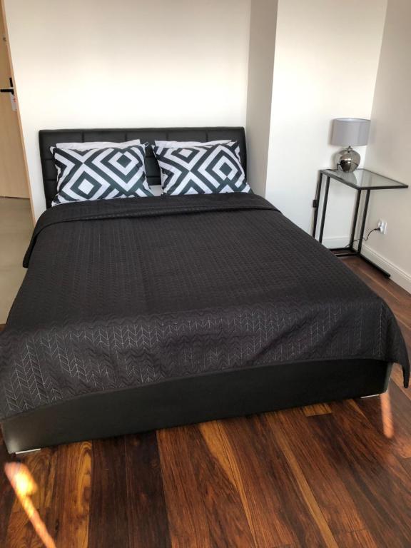a bed with a black comforter on a wooden floor at Apartamenty Platinex 5 in Kraków