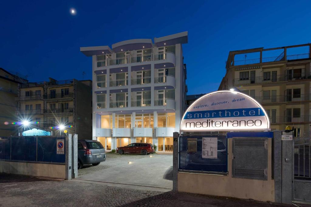 a building with a sign in front of a parking lot at Hotel Mediterraneo in Sottomarina