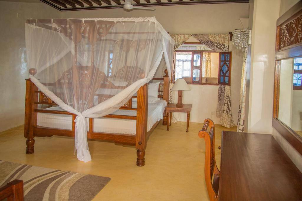 a bedroom with two beds with a canopy at MANDA ISLAND Private Villa in Lamu