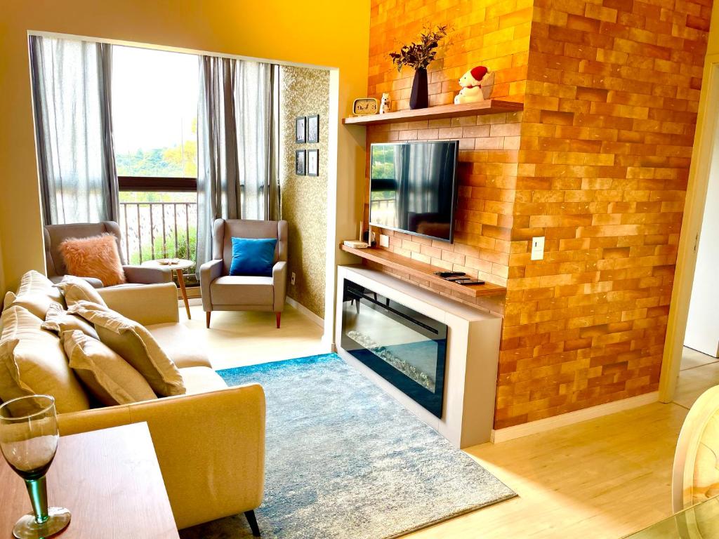 een woonkamer met een open haard en een televisie bij Alto da Montanha VIP Campos in Campos do Jordão