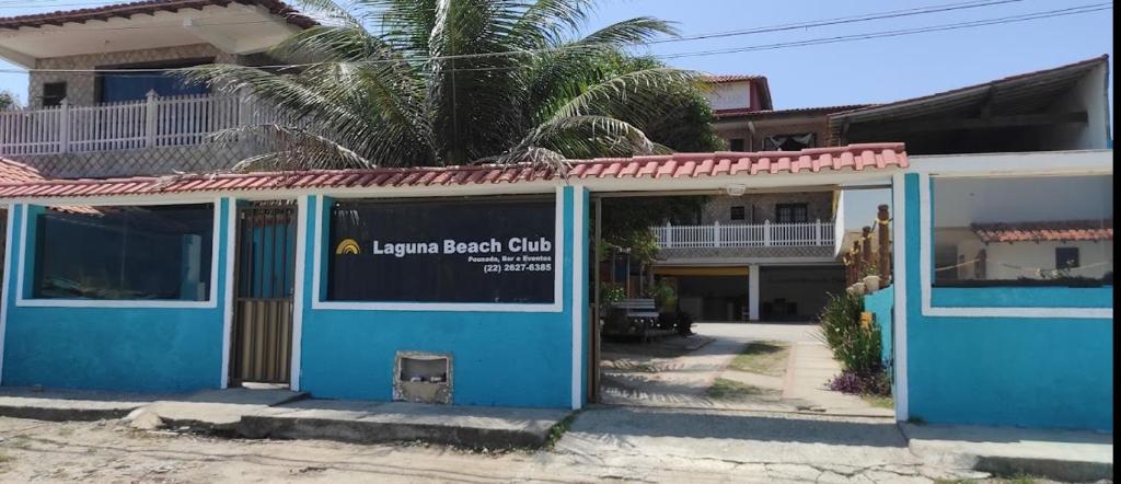 ein blaues Gebäude mit einem Schild davor in der Unterkunft Pousada Laguna Beach Club in São Pedro da Aldeia