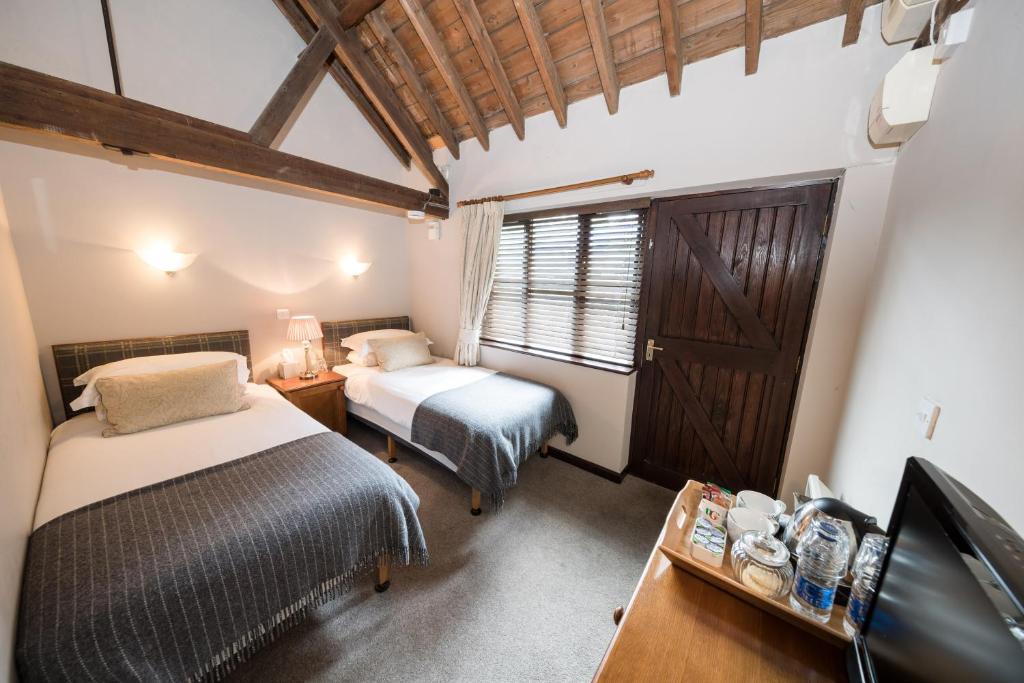 a bedroom with two beds and a tv and a window at The Red Lion Eaton in Norwich