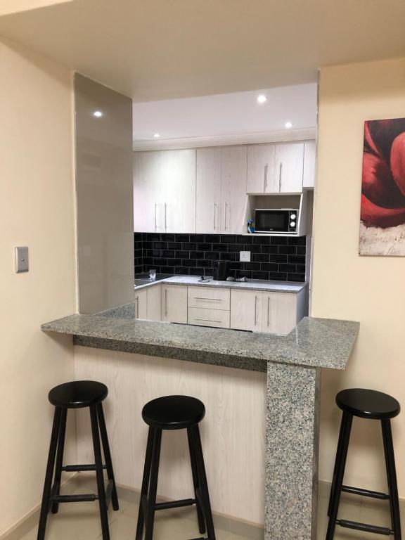 a kitchen with two bar stools and a counter top at Afsaal flats in Amanzimtoti