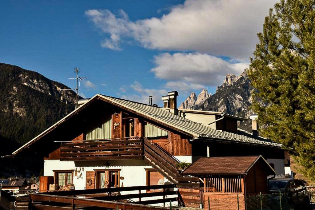 a log house with mountains in the background at Appartamento Mainardi in Auronzo di Cadore