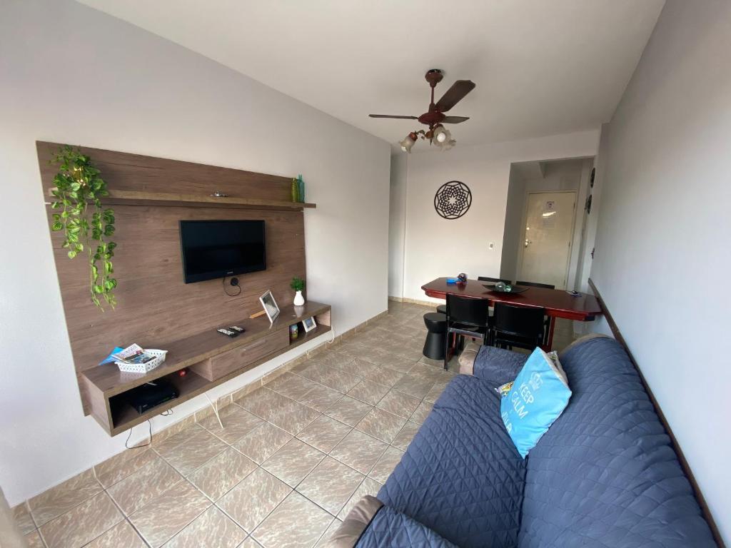 a living room with a blue couch and a flat screen tv at Apto Guarujá - Asturias in Guarujá