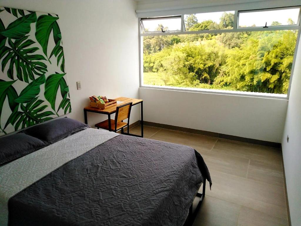 um quarto com uma cama e uma grande janela em Hotel La Aldea del Oriente em Marinilla