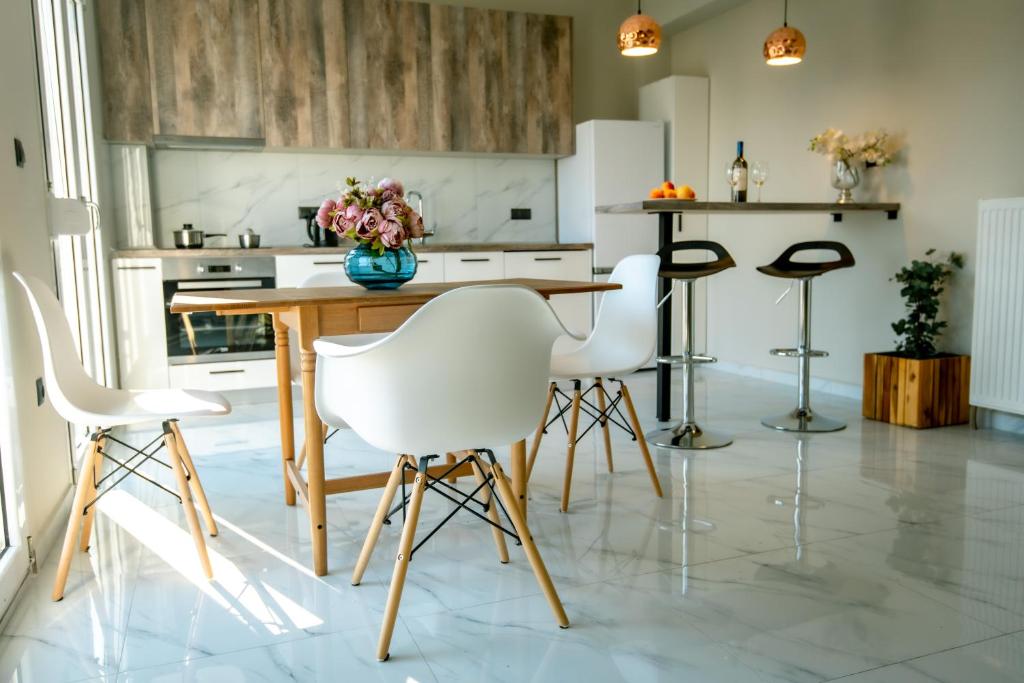 - une cuisine avec une table en bois et des chaises blanches dans l'établissement Miracle Luxury Apartments, à Peraia
