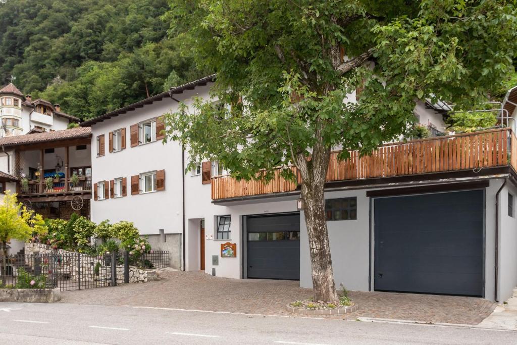 un bâtiment blanc avec deux portes de garage et un arbre dans l'établissement Agritur E-Cinque, à Salorno