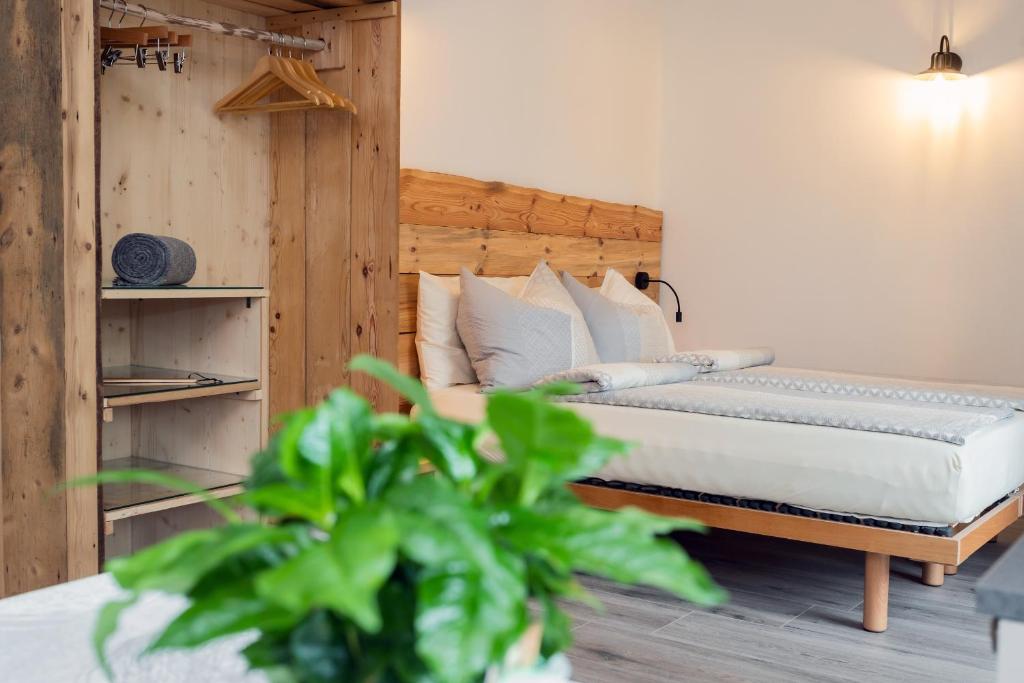 a bedroom with a bed with white sheets and a plant at Agritur E-Cinque in Salorno