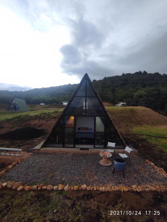 una casa triangular negra con chimenea en un campo en Refugio El Cacique, en Guatavita