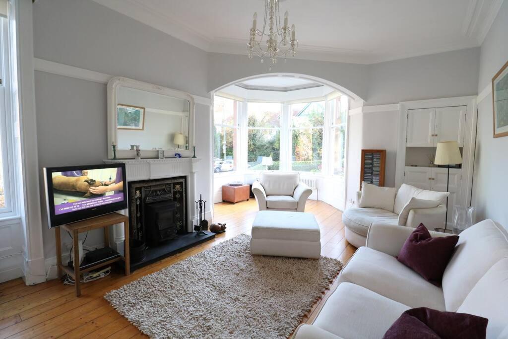 a living room with white furniture and a flat screen tv at Two Bed Holiday Home in Glasgow in Glasgow