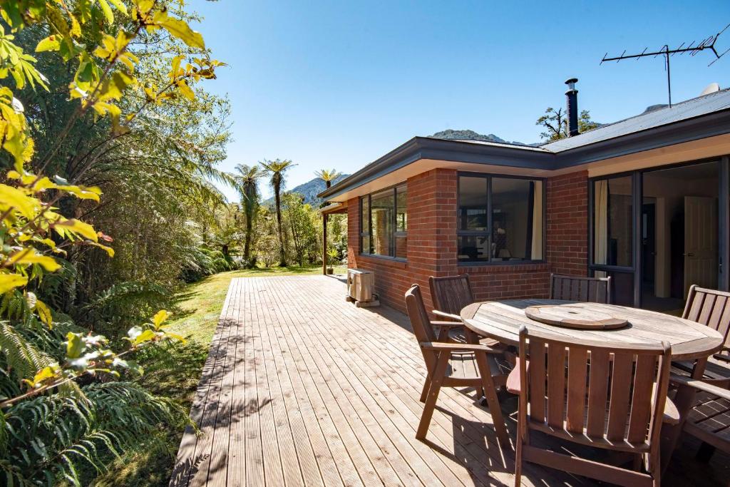 a patio with a table and chairs and a house at Six Kamahi Guest House & Studio Unit in Franz Josef