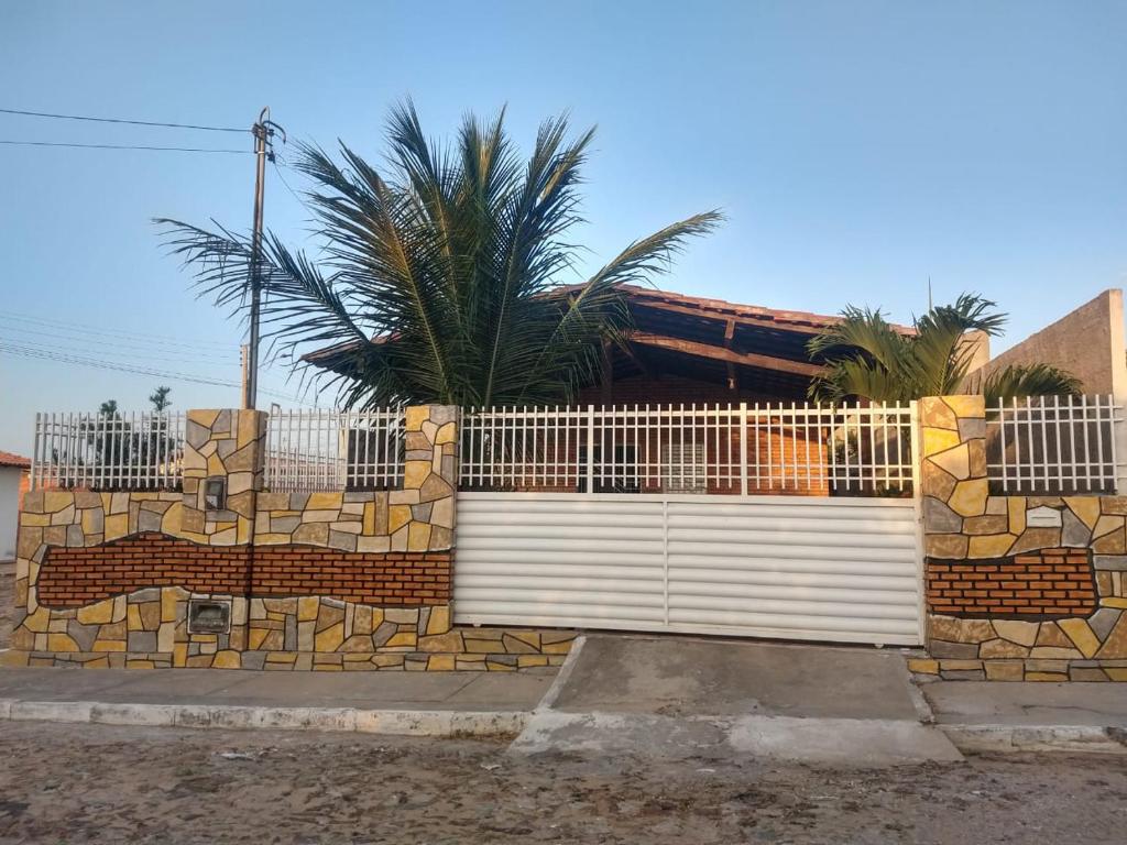 a fence with a white gate in front of a house at Sua casa no litoral in Parnaíba