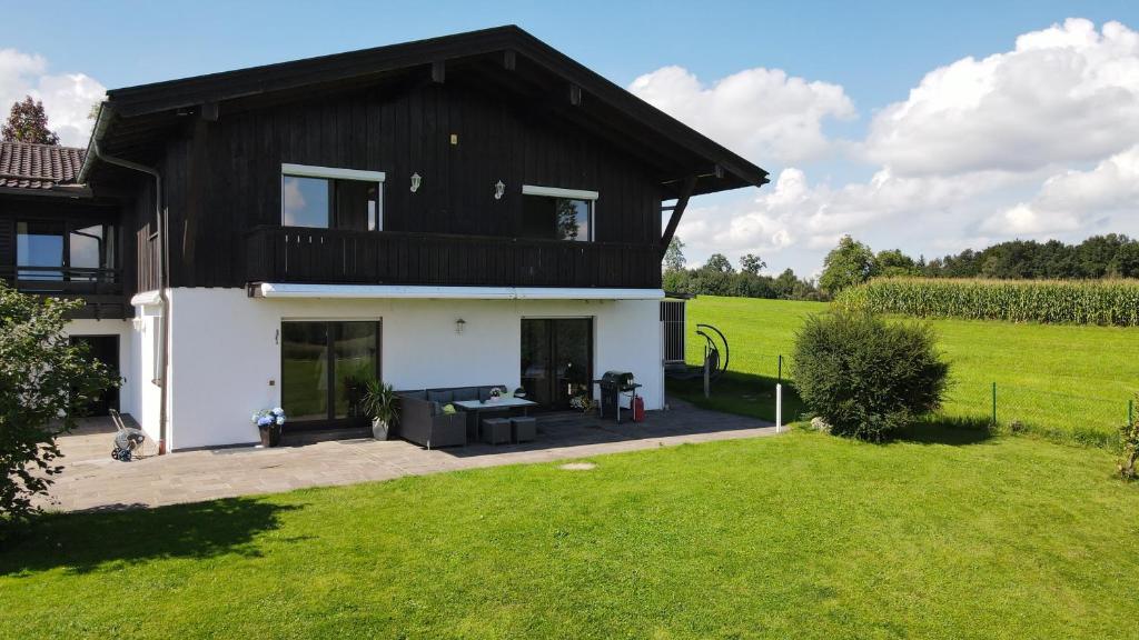 ein Haus mit einem schwarzen Dach und einem grünen Feld in der Unterkunft Schönes Ferienhaus am Herrenberg in Prien am Chiemsee