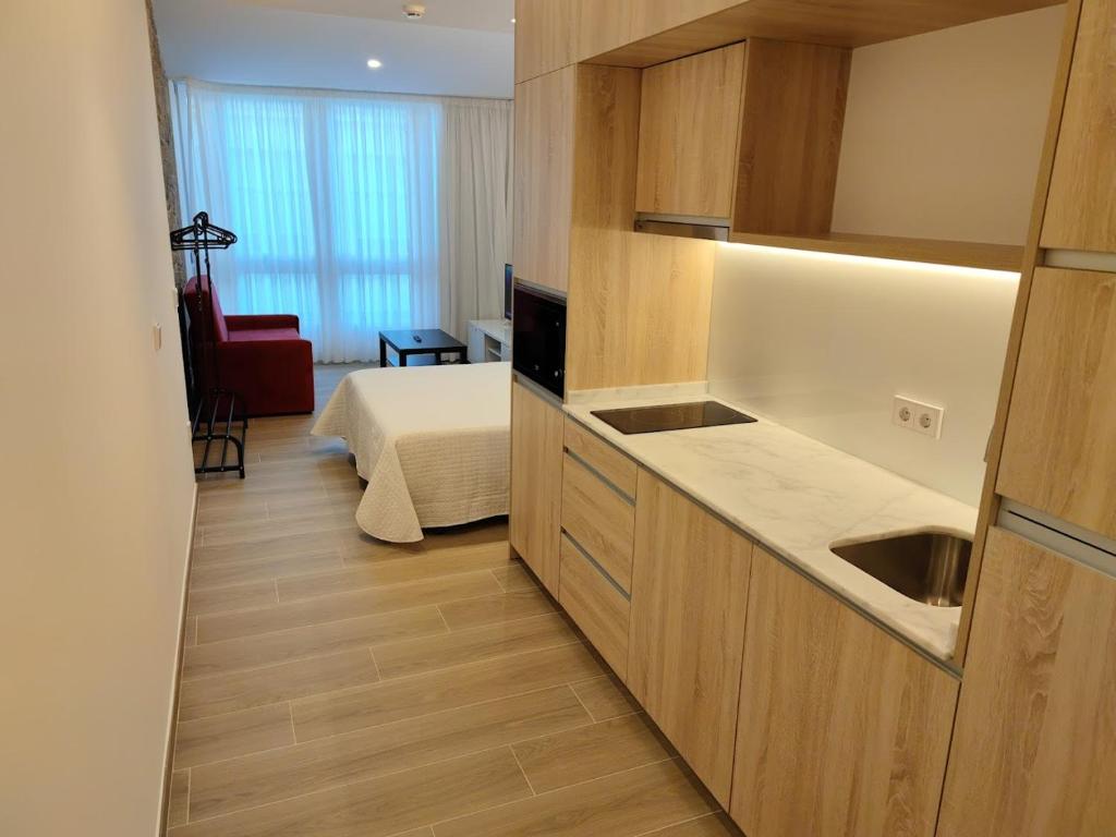 a room with a bed and a kitchen with a sink at Apartamentos A pousa do Asma in Chantada